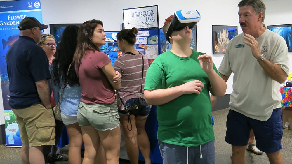 A boy wearing virtual reality goggles to view the sanctuary as a volunteer stands by to assist.