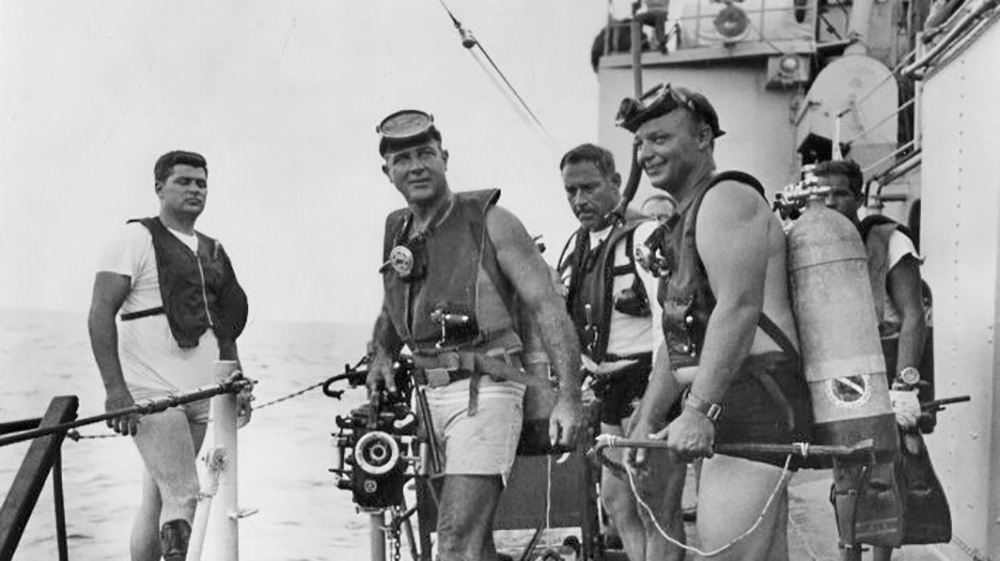 Black and white image of men getting ready to dive off a Navy ship in 1967