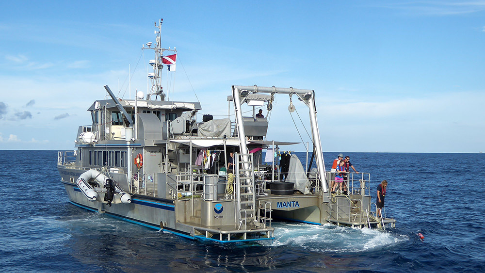 The sanctuary research vessel MANTA at sea with people on the back deck.