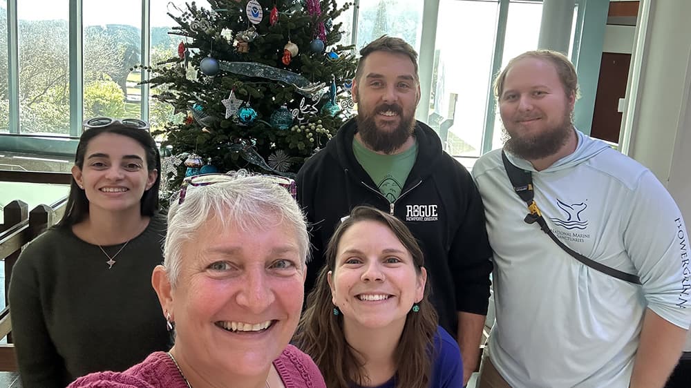 Five sanctuary staff members pose for a selfie in front of the decorated tree
