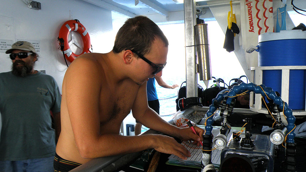 Jake writing down information in a dive log during a teacher expedition