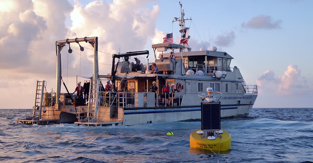 Research Vessel MANTA at sea with a yellow and black buoy in the foreground